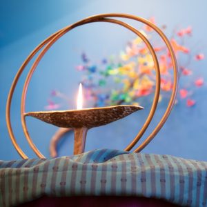 A chalice or wide goblet with a lit candle in the middle surrounded by two decorative circles