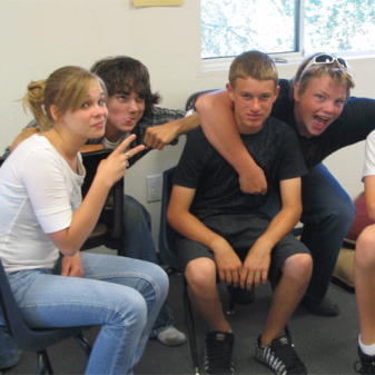 Four teenagers pose while sitting in a religious education room at the church